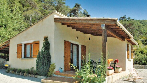 A small, single-story house with a sloped roof, wooden shutters, and a porch with outdoor seating. - 2 bedroom awesome home in Teyssieres (Teyssieres)