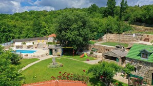 Ein Steinhaus mit Pool, Sitzgelegenheiten im Freien und einem Spielplatz.