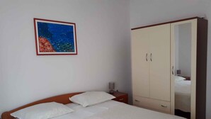 Un dormitorio con cama, mesita de noche, armario y un cuadro en la pared.