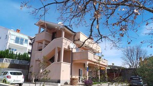 Un edificio residencial de varios pisos con balcones, una entrada para vehículos y automóviles estacionados.