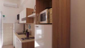 Una cocina con armarios de madera, un refrigerador blanco y un microondas Bosch sobre la encimera.