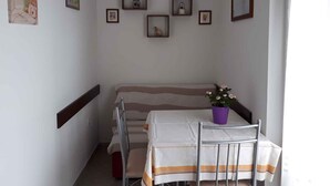 Un pequeño comedor con una mesa, sillas, un sofá y varias fotografías enmarcadas en la pared.