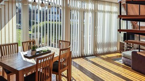 A dining area with a wooden table and chairs, a potted plant, and a view through a window with vertical blinds. - Amazing home in Langelsheim with WiFi (Langelsheim)