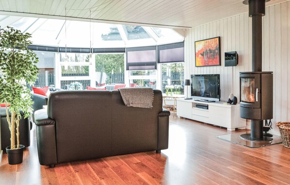A cozy living room with a sofa, TV, and a wood-burning stove. - Beautiful home in Blåvand with sauna (Blåvand)