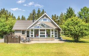 A house with a large glass conservatory, a wooden deck, and a metal roof. - Beautiful home in Blåvand with sauna (Blåvand)