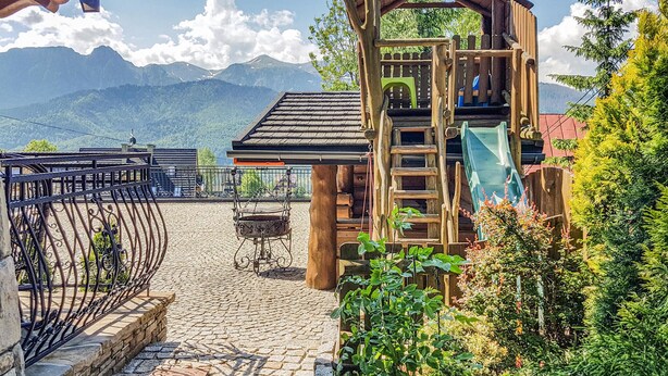Un espace extérieur rustique doté d’une structure en bois, d’une clôture en métal et d’un sol pavé de pierres.