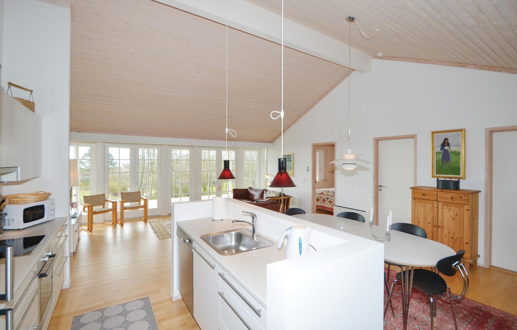 Eine moderne Küche mit einer zentralen Kochinsel, Holzböden und großen Fenstern.