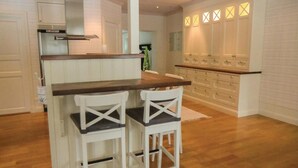 A kitchen with a central island, white bar stools, wooden countertops, and a built-in oven. - Lovely home in Tranås with kitchen (Tranås)