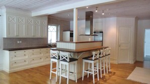 A spacious kitchen with white cabinetry, a central island with bar stools, and a large window providing natural light. - Lovely home in Tranås with kitchen (Tranås)