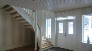 A staircase with wooden steps and white railings leading to a landing. There are two windows on the landing, one with a door and another without. The floor is wooden, and the walls are white with paneling. - Lovely home in Tranås with kitchen (Tranås)