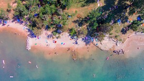 Luchtbeeld van een strand met mensen, parasols en strandstoelen.