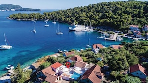 Ein Küstdorf mit klarem, blauem Wasser, Booten und traditionellen Häusern mit roten Dächern.
