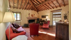 A cozy living room with a fireplace, red leather sofas, and a wooden ceiling. - 3 bedroom amazing home in Anghiari -AR- (Anghiari -AR-)