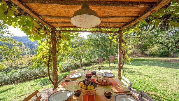 A table set for four with wine glasses, plates, and a basket of fruits. - 3 bedroom amazing home in Anghiari -AR- (Anghiari -AR-)