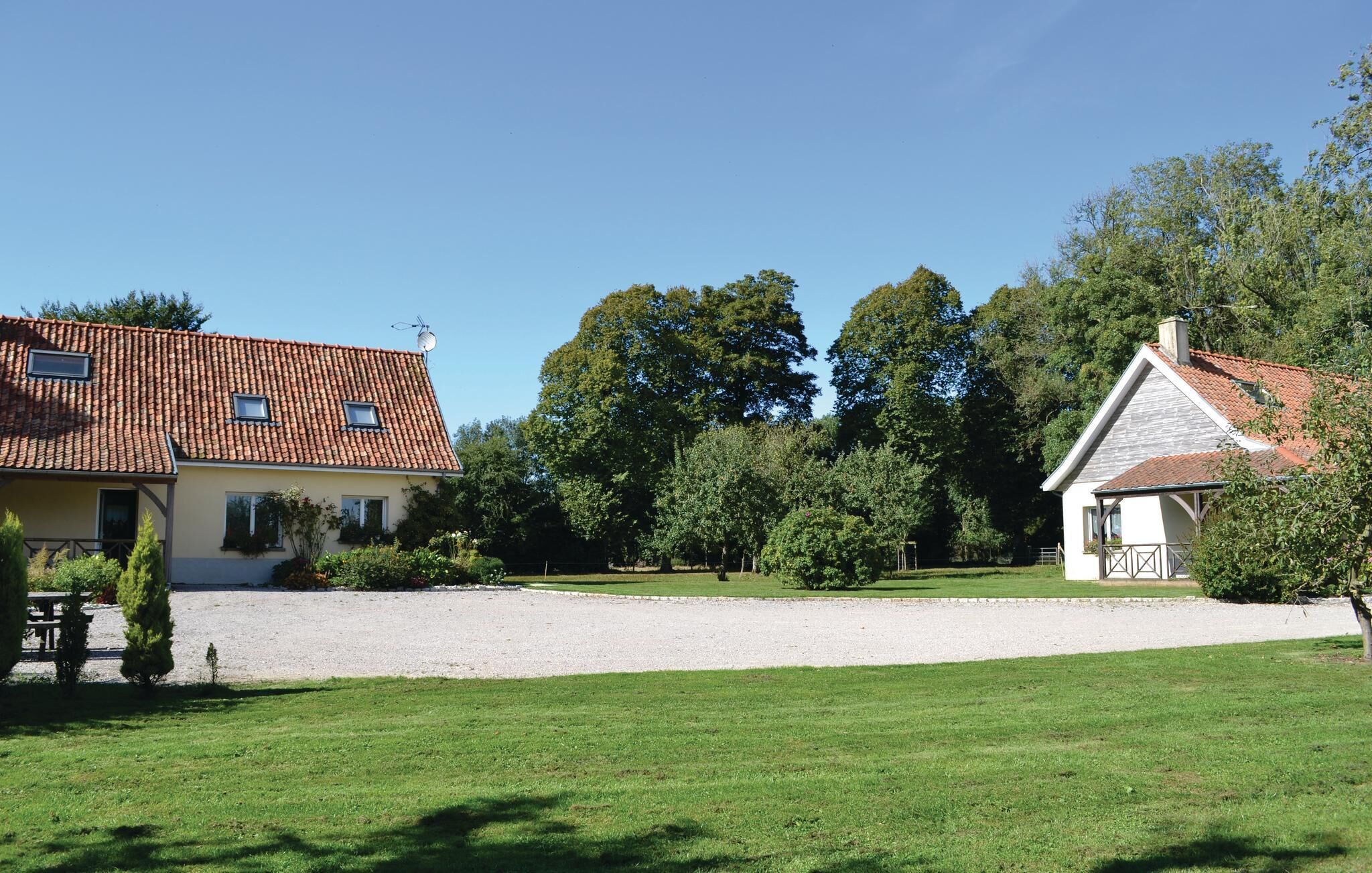A two-story house with a tiled roof, a gravel driveway, and a well-maintained lawn.