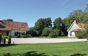 Ein zweigeschossiges Haus mit Ziegeldach, Kiesauffahrt und gepflegtem Rasen.