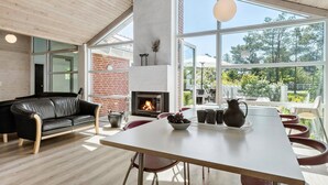 A modern living room with a fireplace, a dining table, and a black leather sofa. - Nice home in Knebel with sauna (Knebel)