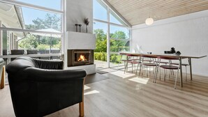 A modern interior with a fireplace, large windows, and a dining area. - Nice home in Knebel with sauna (Knebel)