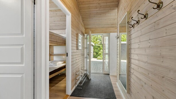 A wooden interior with a bunk bed, a door leading outside, and a hallway with a rug. - Nice home in Knebel with sauna (Knebel)