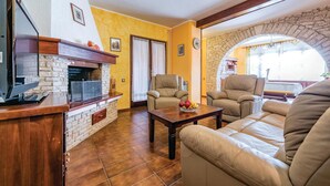 A living room with a stone fireplace, leather sofas, and a dining table with fruit. - Nice apartment in Pula with sauna (Pula)