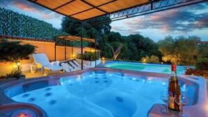 A hot tub with a bottle of champagne, surrounded by lounge chairs and a pool. - Nice apartment in Pula with sauna (Pula)
