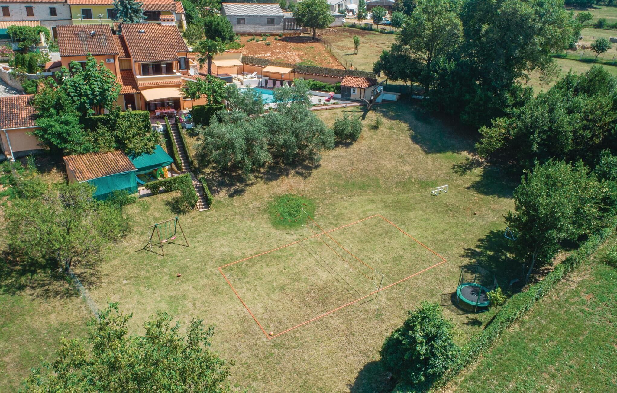 An aerial view of a residential area with houses, a grassy field, and trees.
