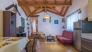 A cozy living room with a wooden ceiling, a red sofa, a television, and a refrigerator.