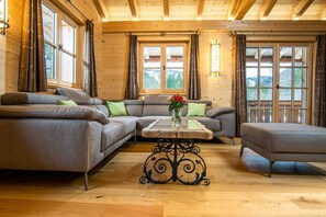En inredning med trädetaljer, en modulsoffa, ett soffbord och ett fönster med gardiner.