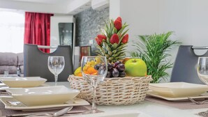 A dining table set with white plates, bowls, and a glass. There is a wicker basket with fruits and a glass of water. - Awesome apartment in Krk with swimming pool (Krk)