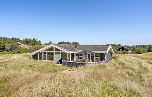 A modern house with a large deck, surrounded by tall grass and trees. - Amazing home in Løkken with sauna (Løkken)