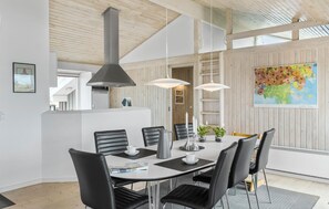 A modern dining area with a white table, black chairs, pendant lights, and a painting on the wall. - Amazing home in Løkken with sauna (Løkken)
