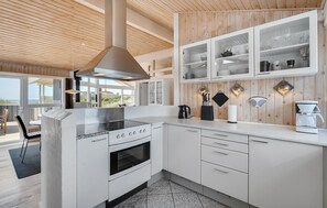 A modern kitchen with white cabinetry, a stainless steel stove, and a large island. - Amazing home in Løkken with sauna (Løkken)