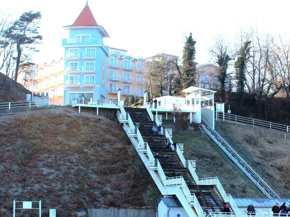 A set of outdoor stairs leading up to a building with a red roof and multiple windows.