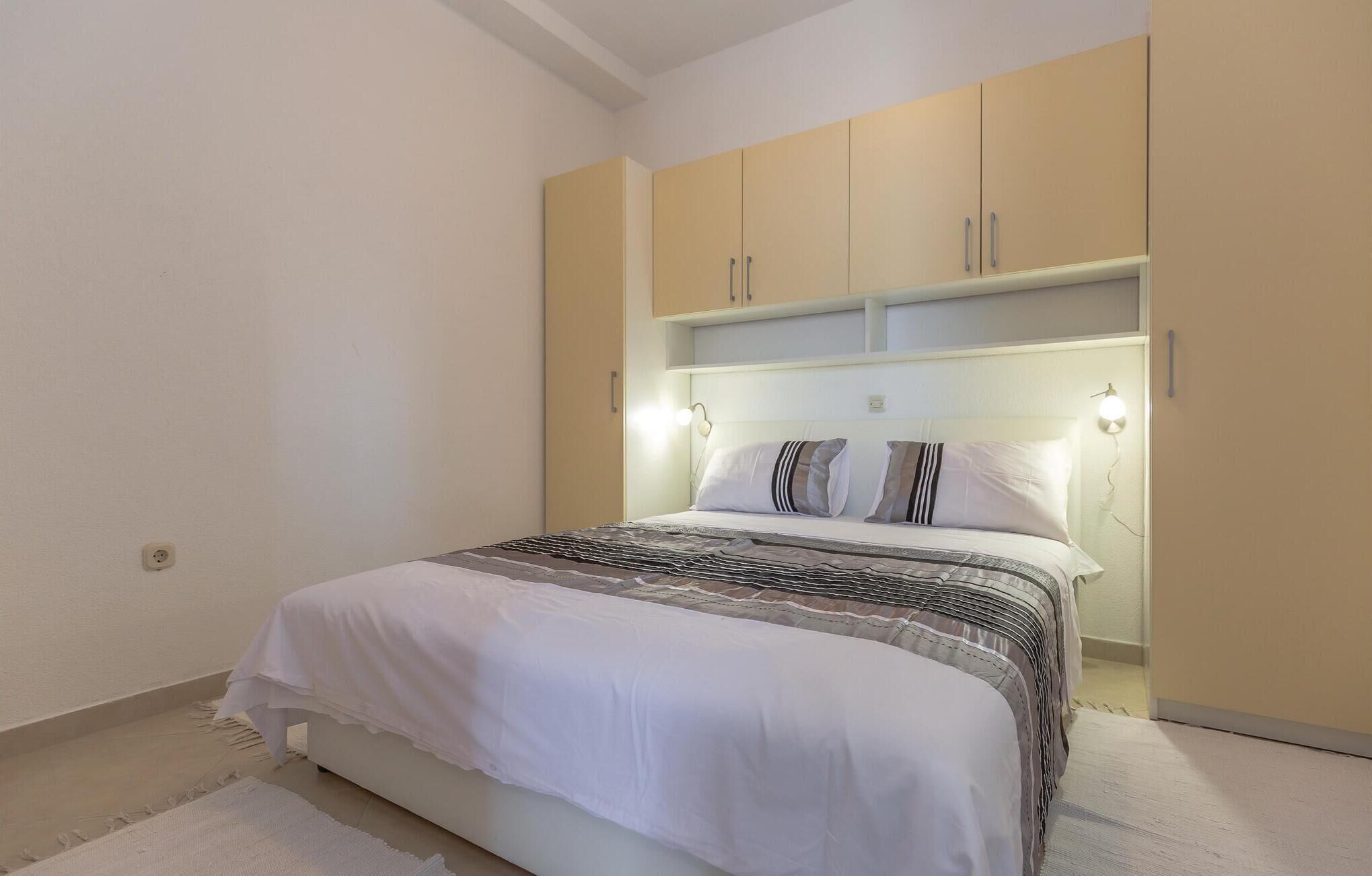 A bedroom with a bed, white bedding, and a headboard with built-in lighting.