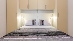 A bedroom with a bed, two bedside lamps, and a headboard. - Beach front home in Podgora with WiFi (Podgora)