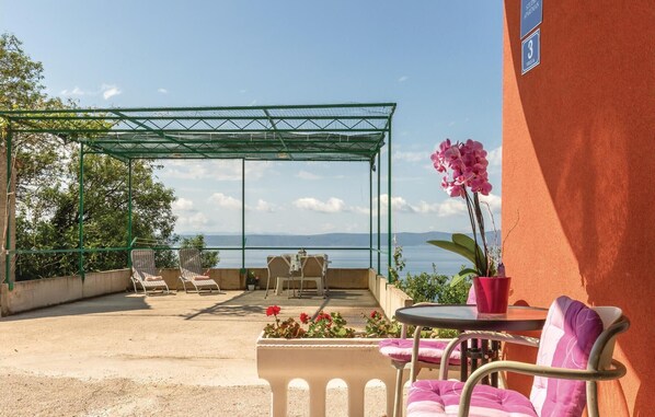 A terrace with a covered seating area, a table, and a potted orchid. - Beach front home in Podgora with WiFi (Podgora)