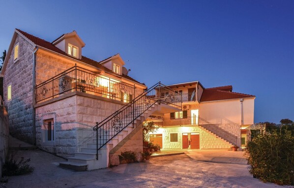 Enter through a charming wooden door to a two-story home with a balcony and a beautifully maintained garden.