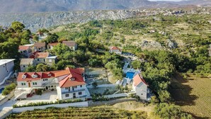 A hillside village with traditional stone houses, a swimming pool, and terraced fields.