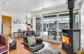 Een gezellige woonkamer met een leren bank, een open haard en een eethoek met een tafel en stoelen.