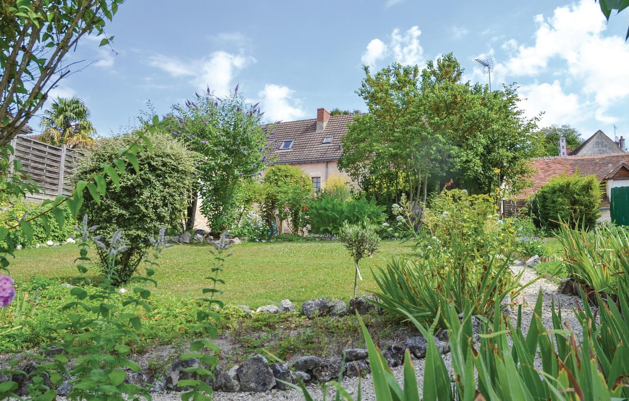 Una casa con jardín, césped y un muro de piedra.