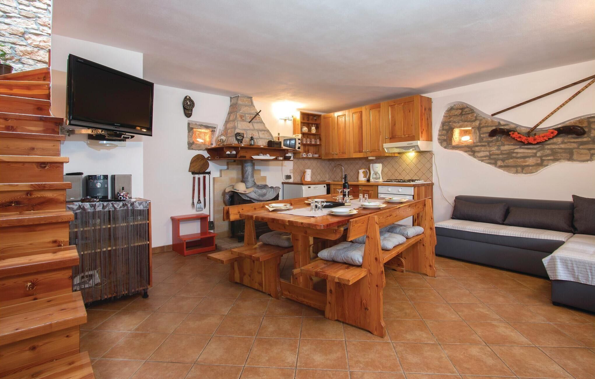 Una cocina acogedora con armarios de madera, una pared de piedra y un televisor de pantalla plana montado sobre la encimera.