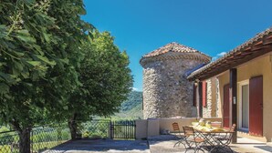 A stone tower, a dining table with chairs, and a fenced patio area. - Amazing home in Flaviac (Flaviac)