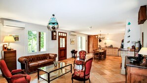 A spacious living room with a brown leather sofa, a glass coffee table, and two red armchairs. A dining area with a wooden table and chairs is visible in the background. - Amazing home in Flaviac (Flaviac)