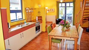 Eine Küche mit Holztisch und -stühlen, einem Fenster und einer Treppe.