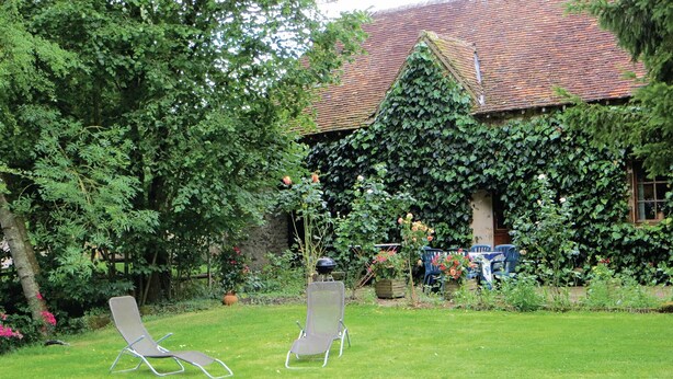 A garden with two lawn chairs, a stone wall, and a house partially covered by ivy. - Gorgeous home in Vernie with WiFi (Vernie)