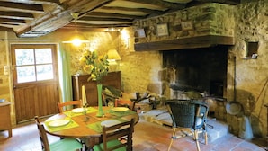 A rustic dining area with a stone fireplace, wooden beams, and a table set for four. - Gorgeous home in Vernie with WiFi (Vernie)