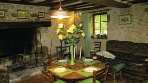 A rustic dining room with a stone wall, wooden beams, a fireplace, and a dining table set for four with green placemats and candles. - Gorgeous home in Vernie with WiFi (Vernie)