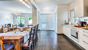 Une cuisine spacieuse avec un coin repas, comprenant une grande table, des chaises et une cuisinière moderne.