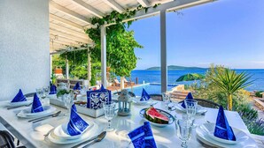 Une table dressée pour le dîner, avec vue sur la mer et une piscine.