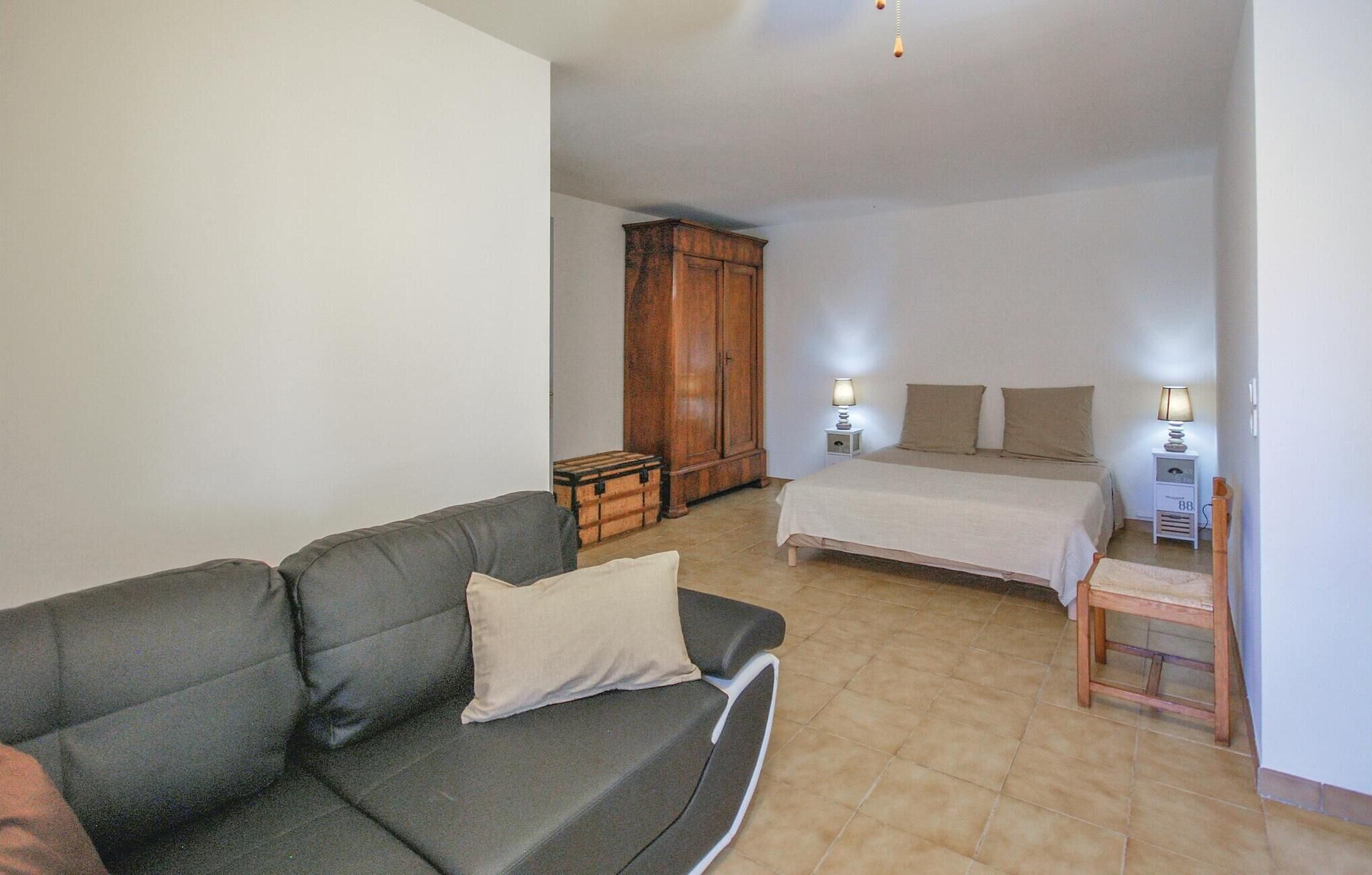 Un dormitorio con cama, mesitas de noche, armario y sofá.